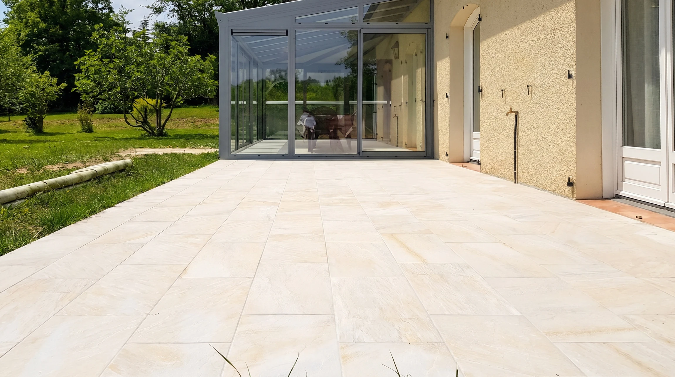 Chantier extérieur de carrelage avec ouvrier à genoux appliquant de la colle sur une dalle