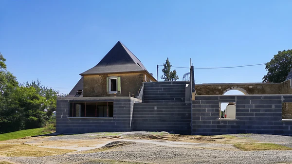 Ouvrier professionnel en tenue bleue et casquette utilisant un marteau pour démolir un mur intérieur fissuré